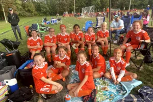 The girl's soccer team enjoying a picnic on the field post-game